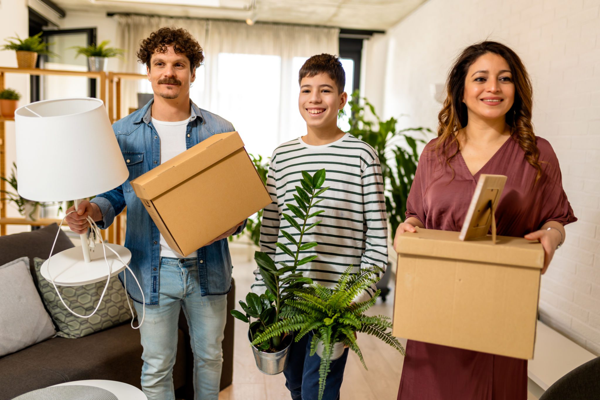 Family moving with boxes and plants.